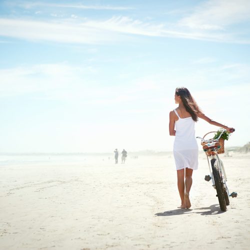 Woman walking with bicycle along beach sand summer lifestyle carefree